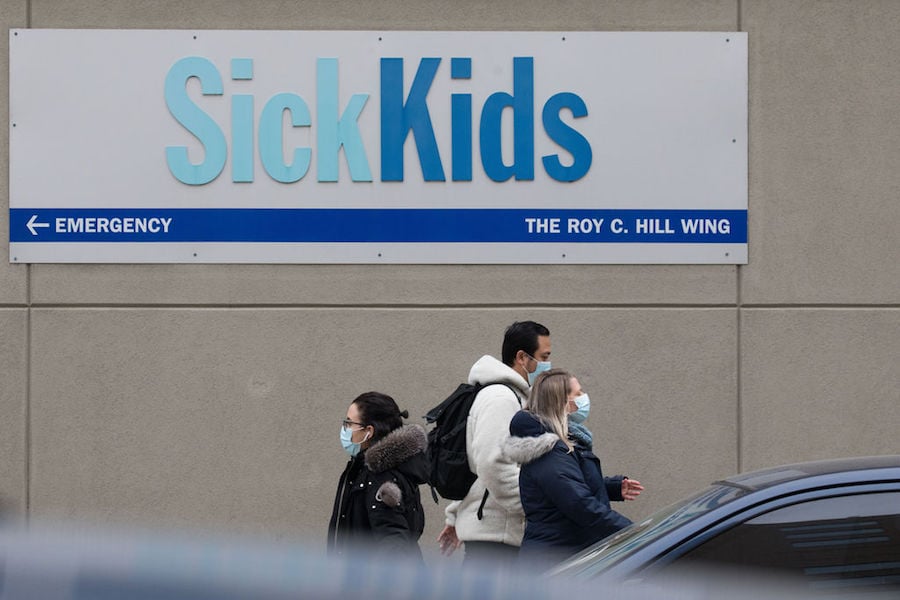 A photo of people walking past SickKids hospital in Toronto