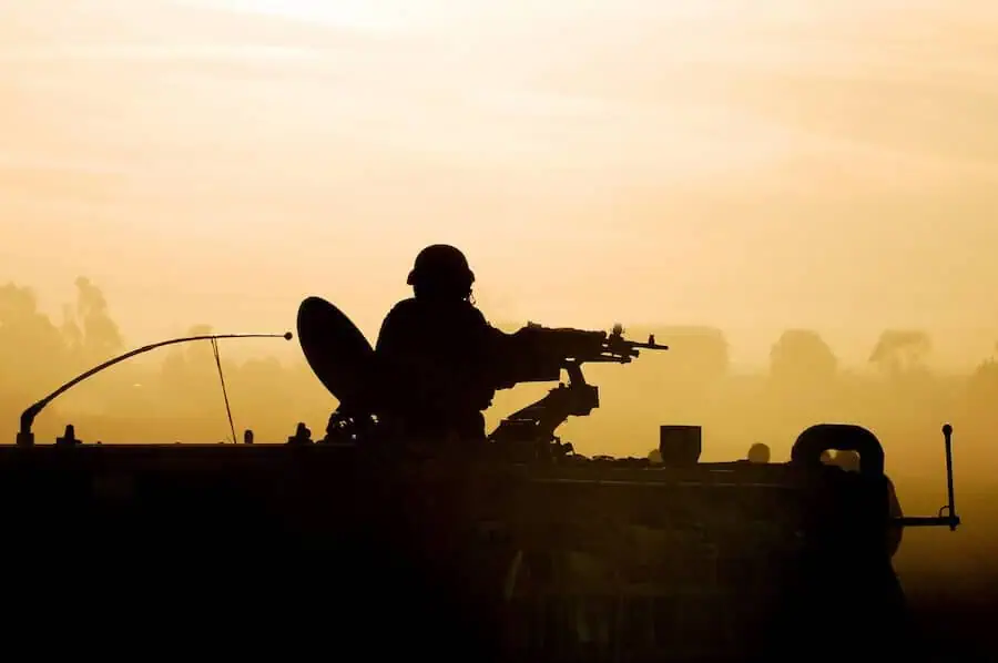 A silhouette of an army soldier preparing tank weapons at sunset