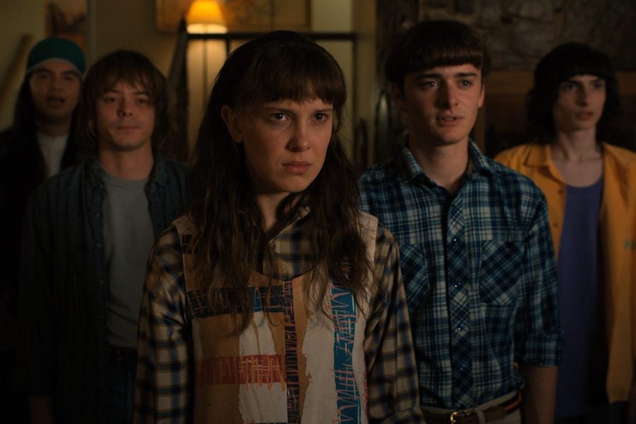 Horror movie scene featuring teenagers with worried expressions in a dimly lit room, emphasizing suspense and youthful fear, perfect for online articles about teen horror films.