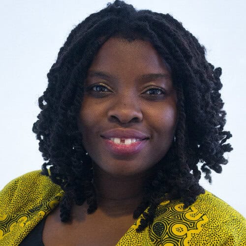 Vibrant portrait of a woman with natural dreadlocks wearing a yellow patterned top for NOW Toronto news images.
