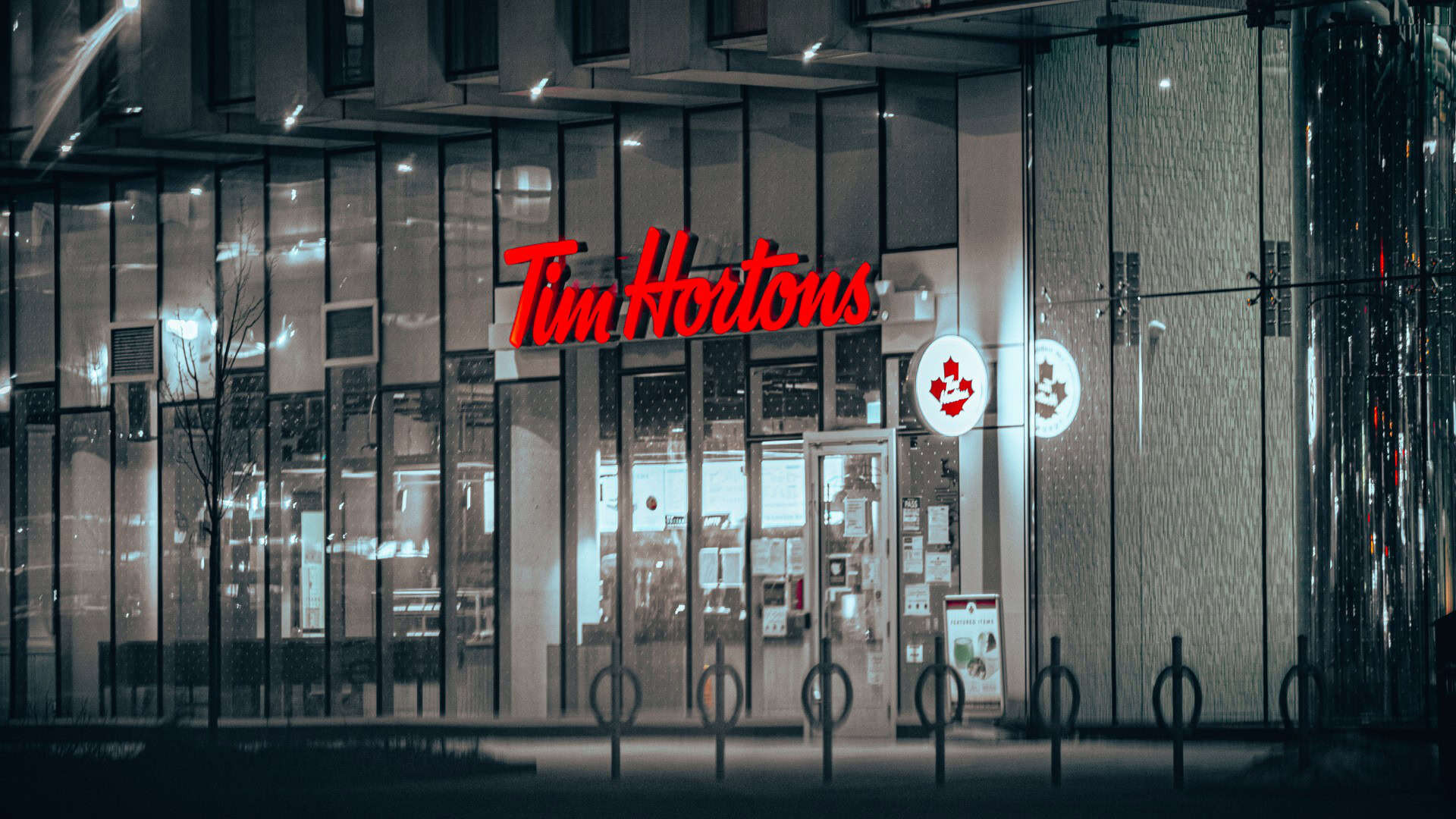Modern Tim Hortons location in Toronto with illuminated signage and reflective glass exterior.