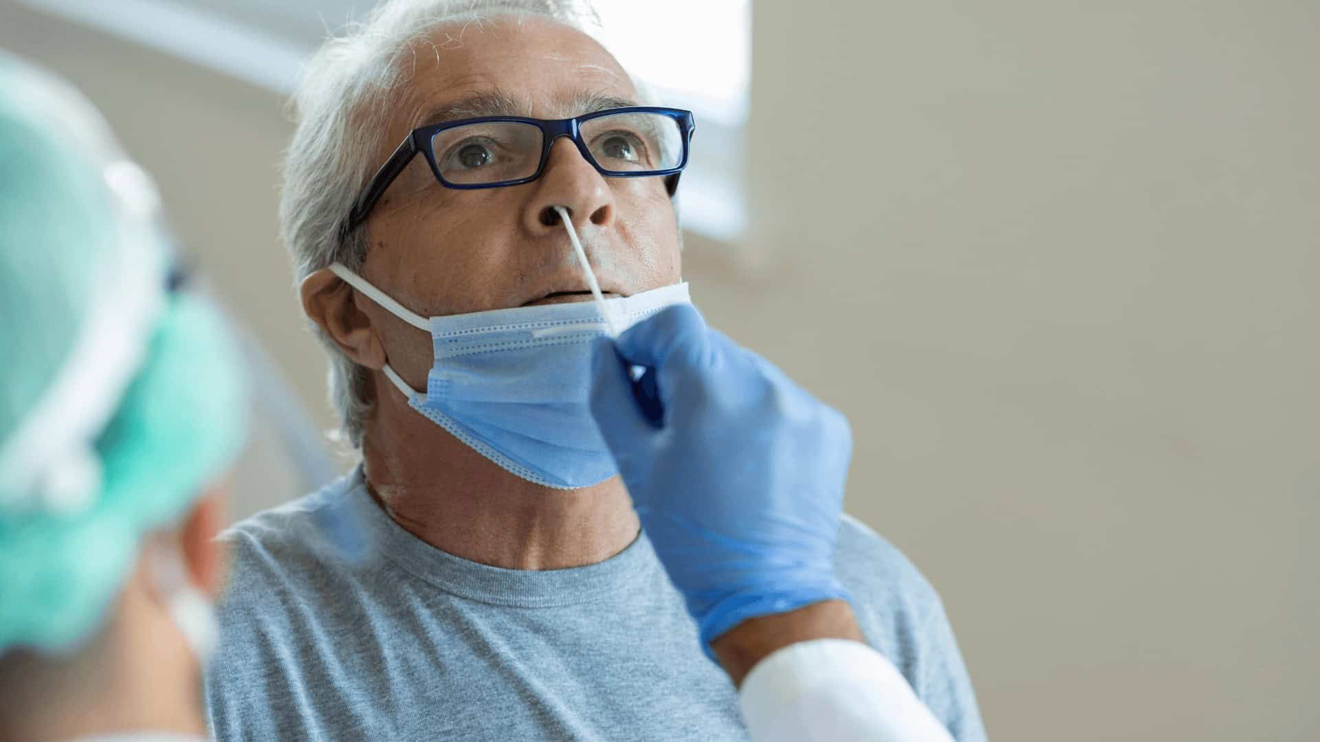 Senior man receiving COVID-19 nasal swab test at healthcare facility in Toronto, healthcare workers conducting COVID testing for seniors, pandemic health screening in Toronto.