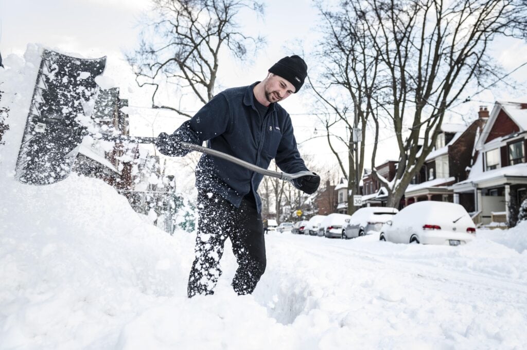 Shoveling snow on a residential street in Toronto during winter.