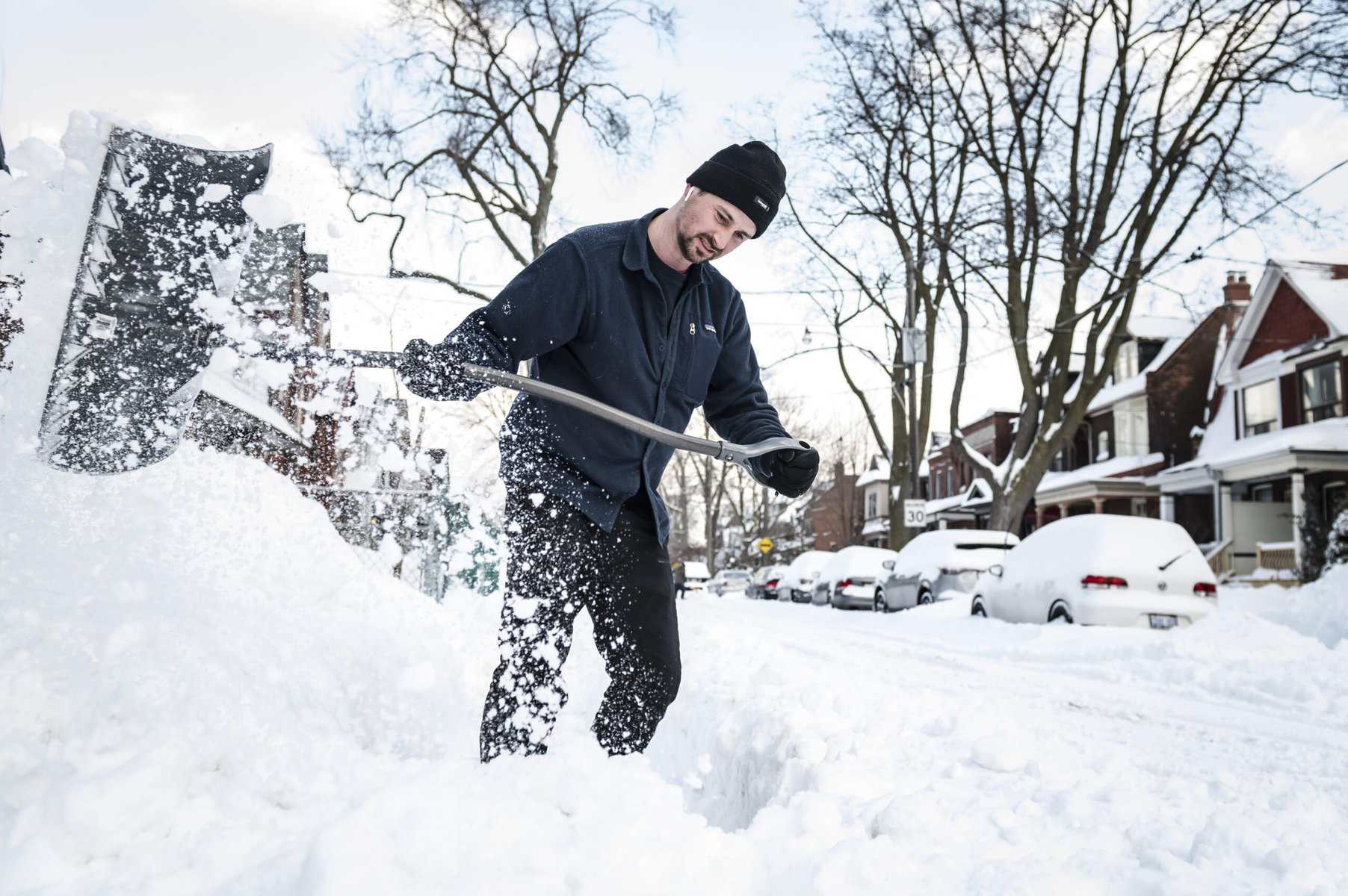 Shoveling snow on a residential street in Toronto during winter.