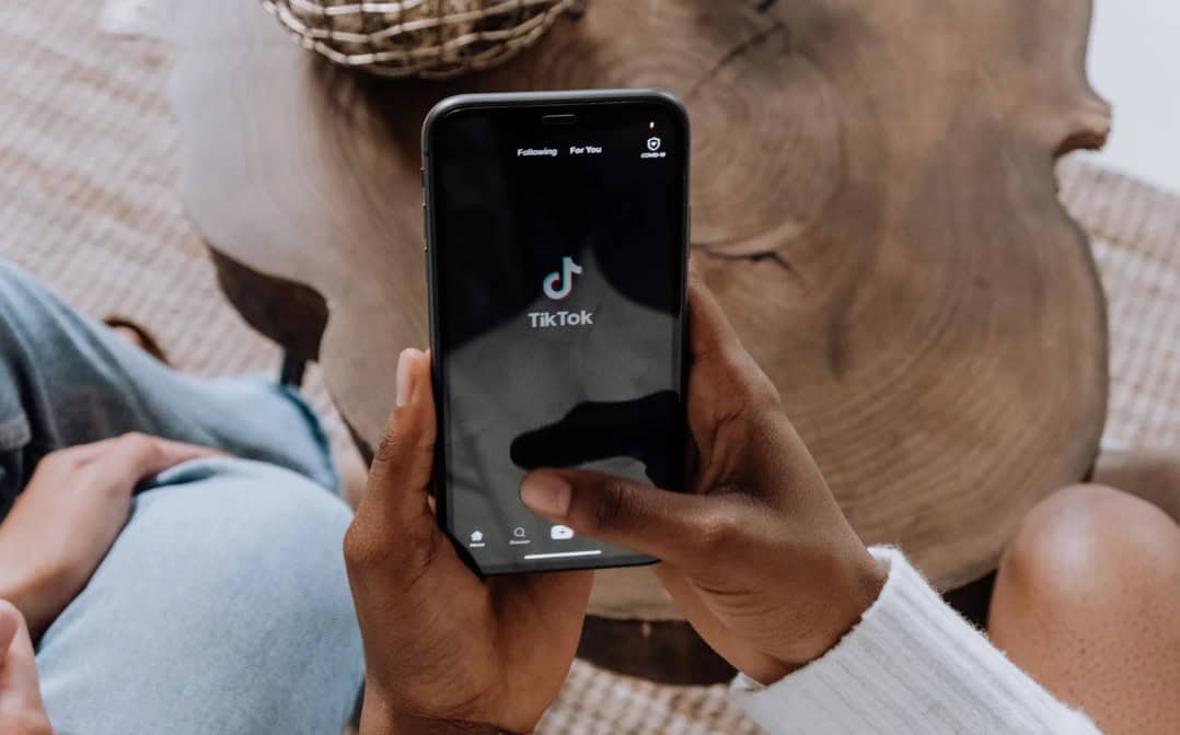 TikTok app on smartphone; person holding mobile device displaying TikTok logo; social media trend in Toronto lifestyle; digital entertainment in Toronto; person using TikTok in Toronto.