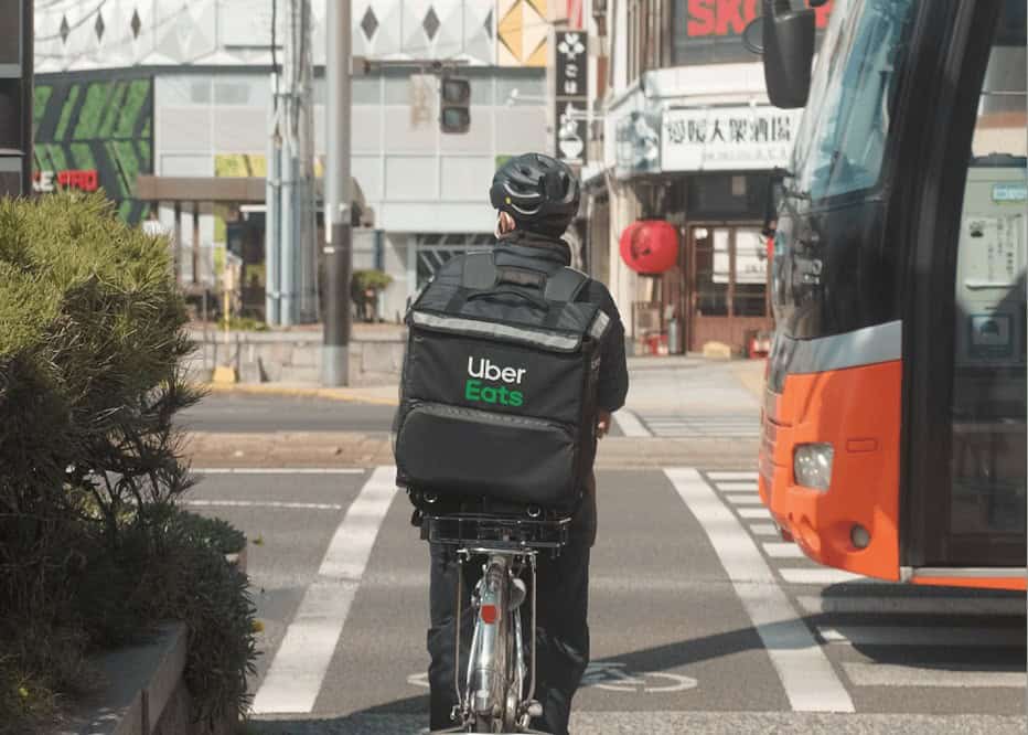 Bike courier delivering food for Uber Eats in downtown Toronto, highlighting urban delivery services and eco-friendly transportation.