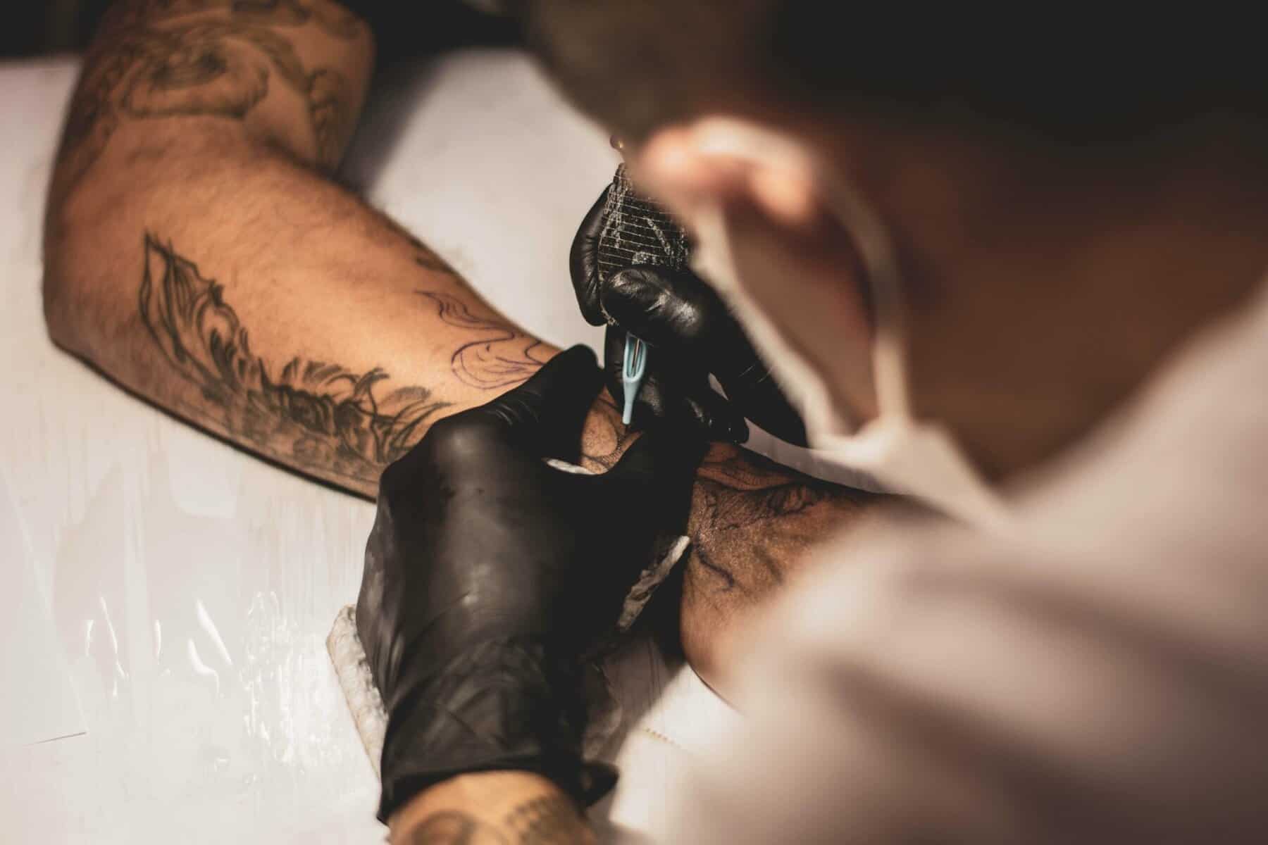 Vegan tattoo artist creating artwork on client's arm in tattoo studio, emphasizing body art and tattoo culture in Toronto, Ontario.