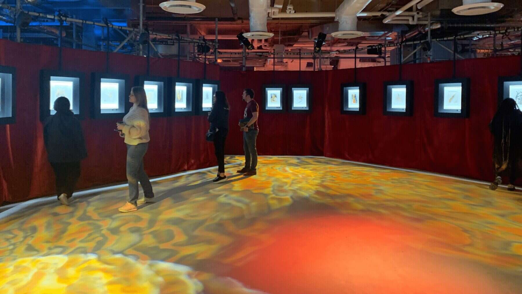 Colorful digital art exhibition at NOW Toronto arts event featuring illuminated framed artworks on red walls.
