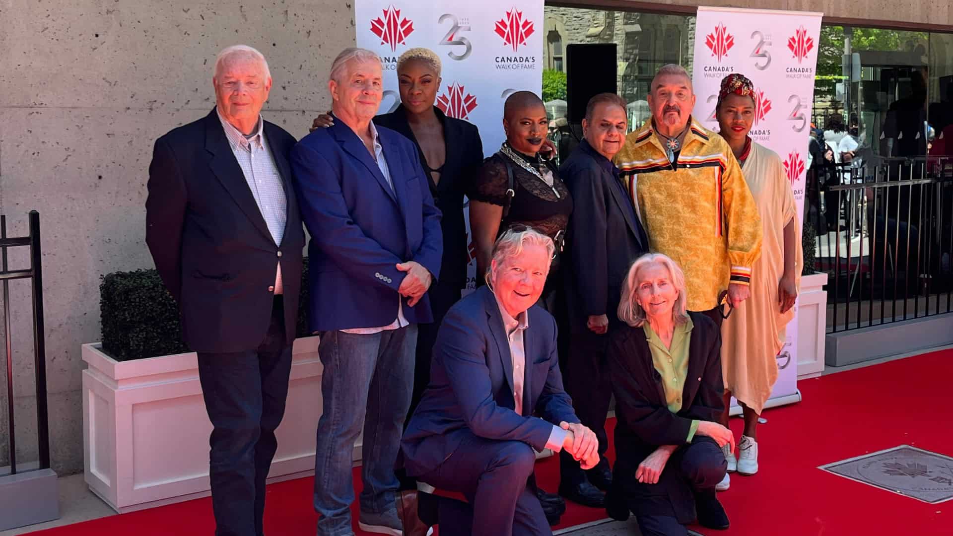 Diverse group of people attending Canada's Walk of Fame event in Toronto, celebrating Canadian entertainment legends, with red carpet and promotional banners in background.