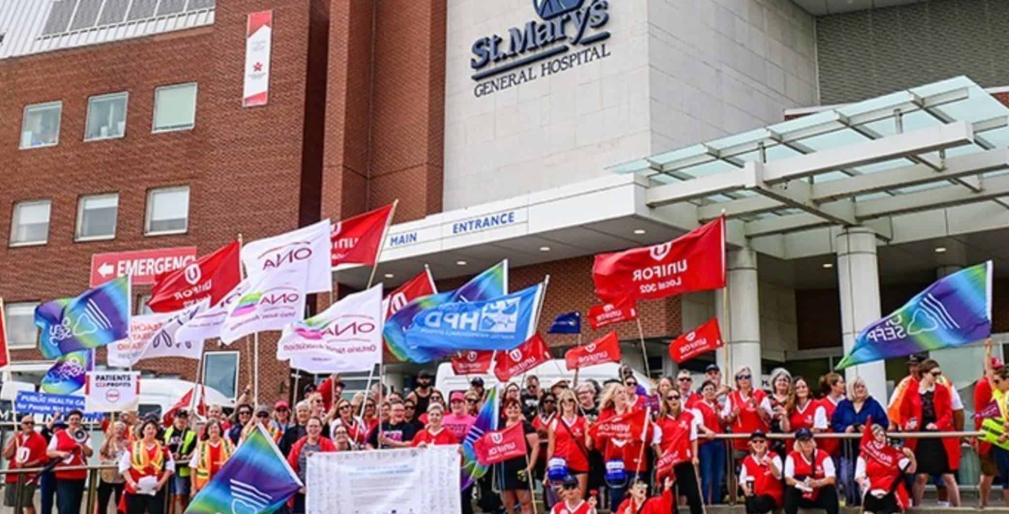 Protest outside St. Mary's General Hospital in Toronto, showcasing healthcare workers holding flags and banners, highlighting community support and employment advocacy.