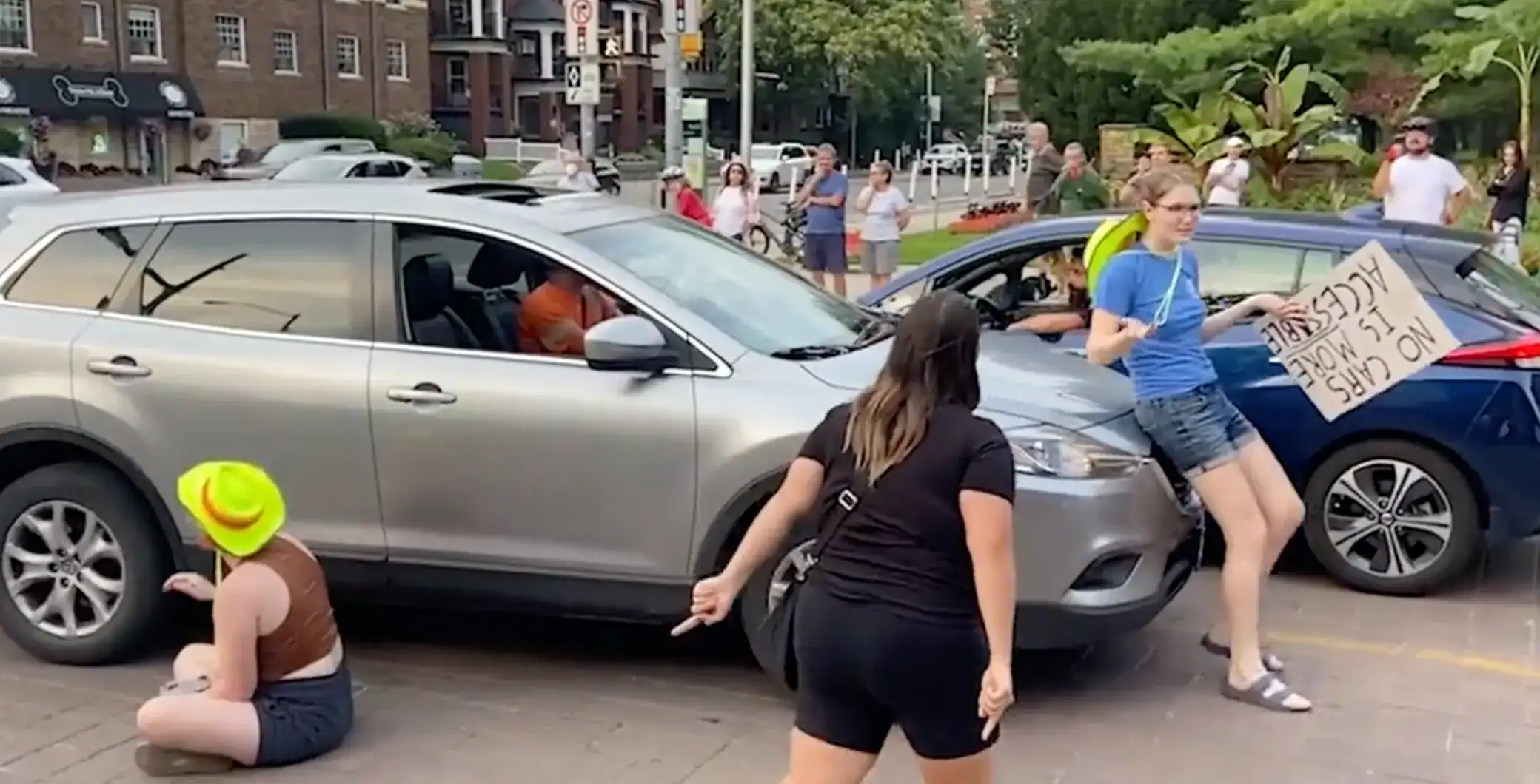 Protesters blocking cars during a climate change demonstration in downtown Toronto, with signs advocating for climate action and environmental awareness.