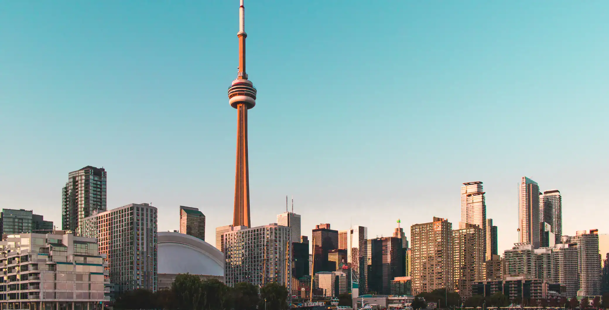 Toronto skyline with CN Tower and modern skyscrapers in downtown Toronto at sunset.