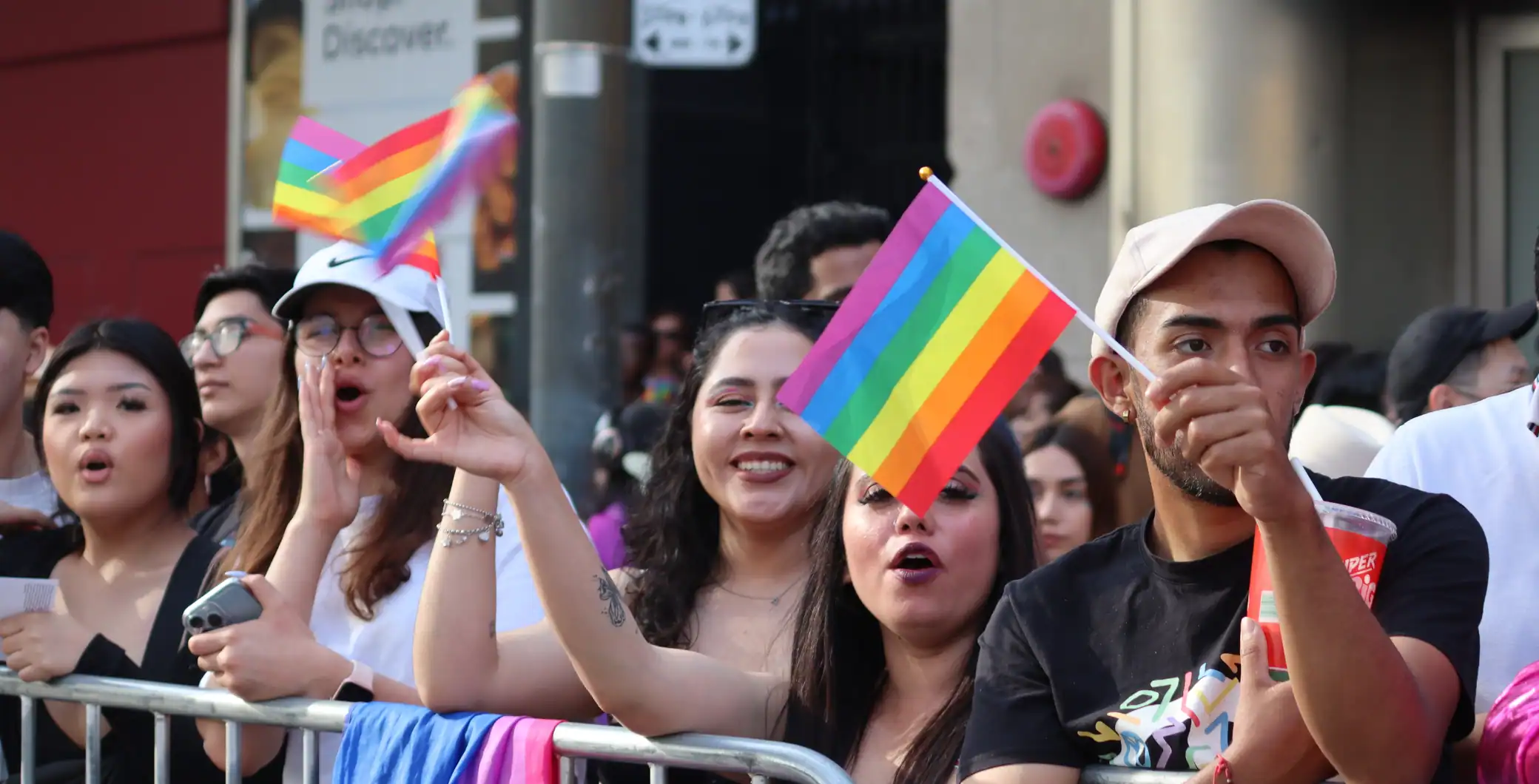 Vibrant LGBTQ pride parade in downtown Toronto with diverse crowd holding rainbow flags and celebrating inclusivity and diversity.