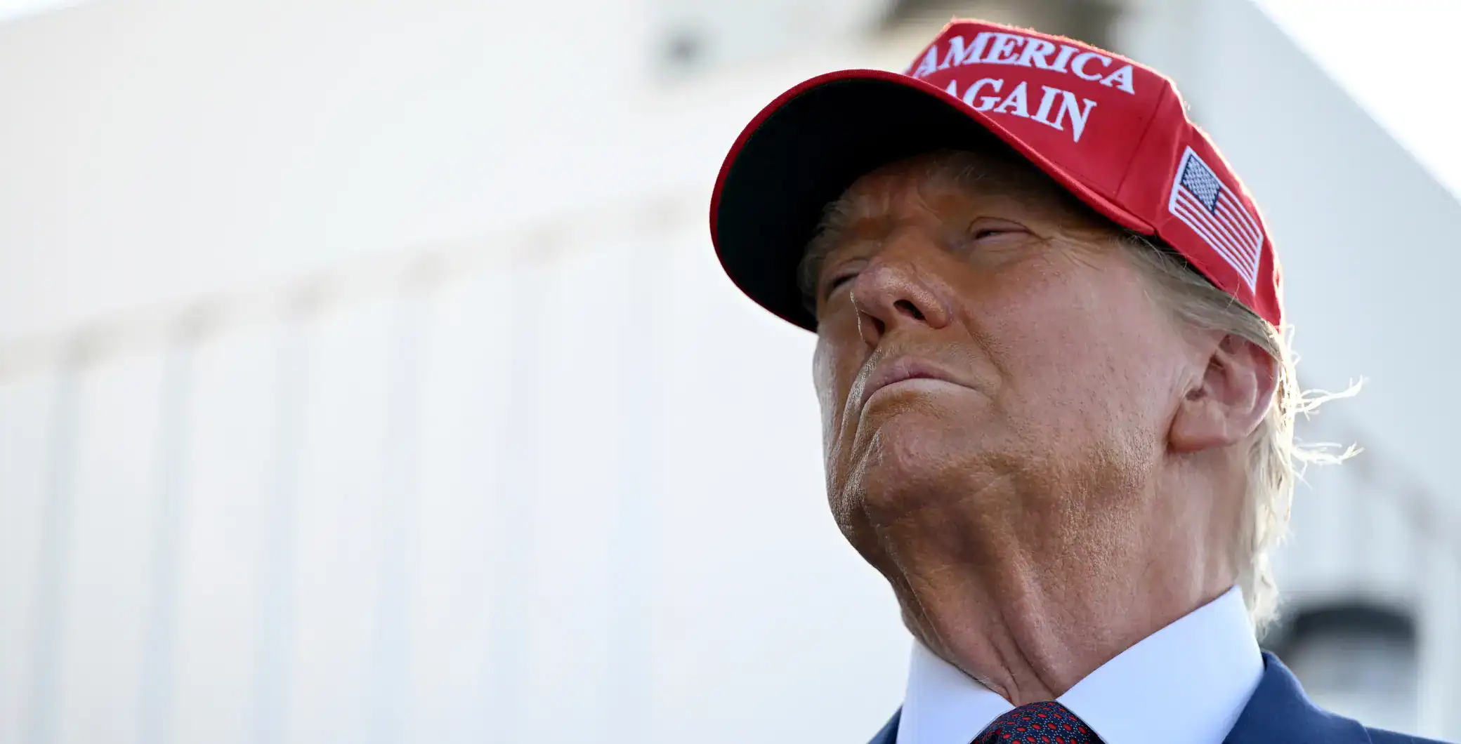 Red "Make America Great Again" hat worn by Donald Trump, close-up shot, political rally, supporter merchandise, American politics, patriotic accessories.