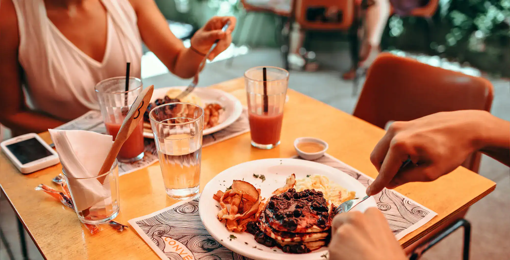 Delicious breakfast with pancakes, bacon, and drinks at an outdoor cafe in Toronto, emphasizing local food scene and breakfast options.
