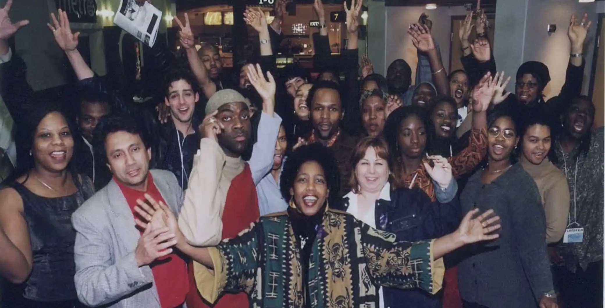 Diverse group of people celebrating and waving at an event in Toronto, capturing a lively and inclusive atmosphere.
