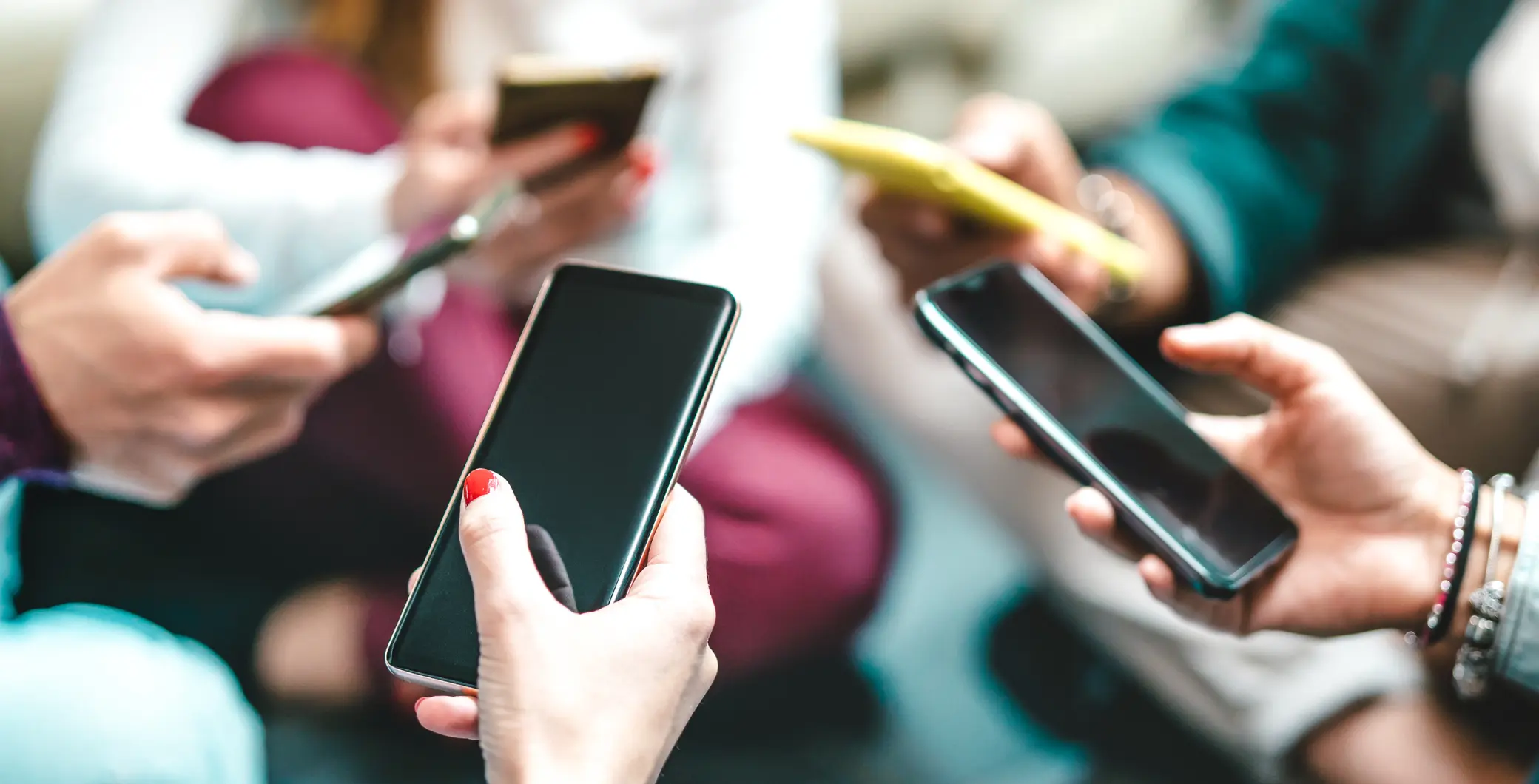 Group of diverse people holding and using smartphones in a social setting, highlighting technology and communication in Toronto.