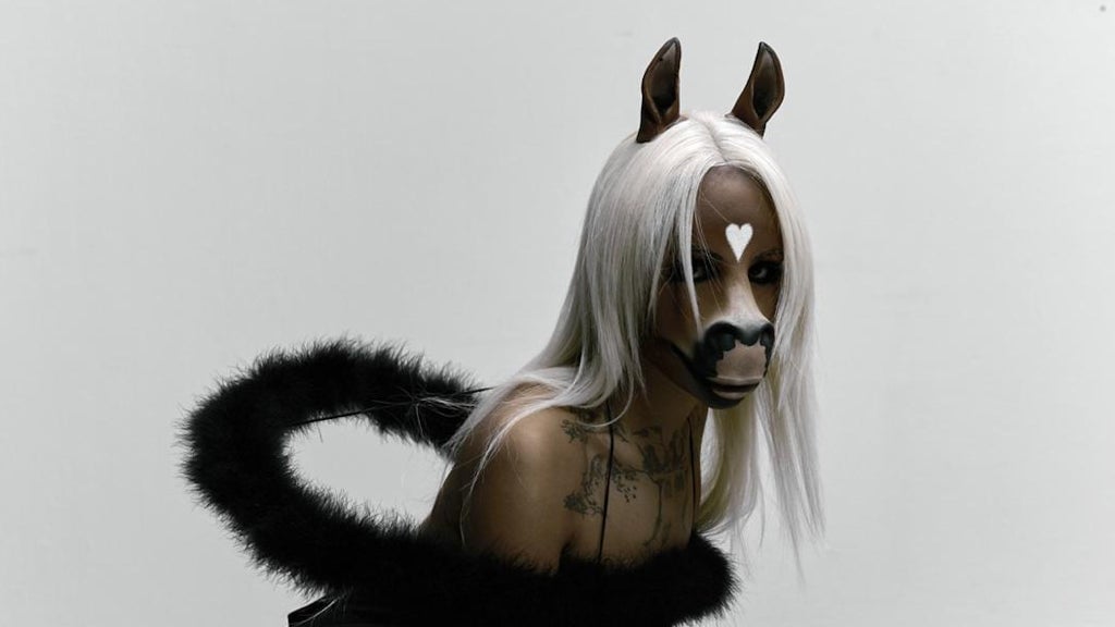 A person wearing a detailed animal-inspired mask with white hair and black fur accents, participating in a Toronto carnival event, showcasing vibrant costume and cultural celebration.
