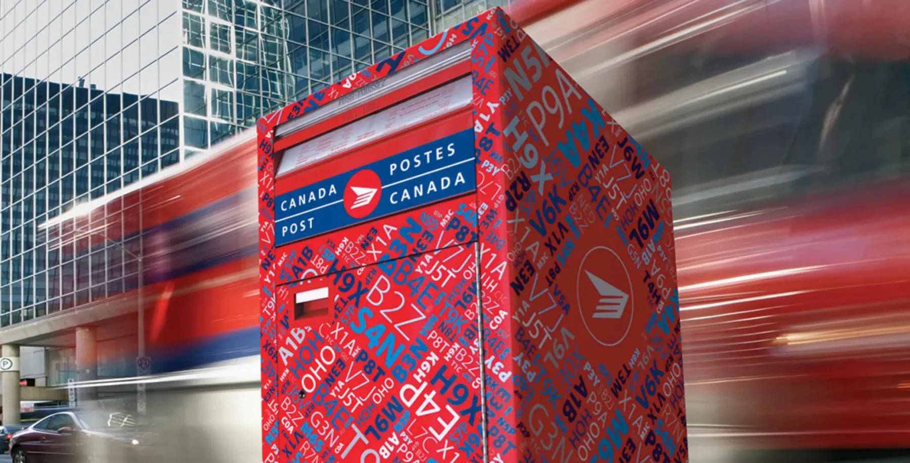 Canada Post mailbox in downtown Toronto with modern glass buildings in the background, capturing urban postal service infrastructure and cityscape.