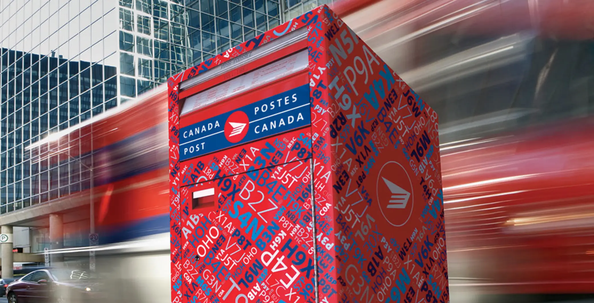 Canada Post mailbox in downtown Toronto with modern glass buildings in the background, capturing urban postal service infrastructure and cityscape.