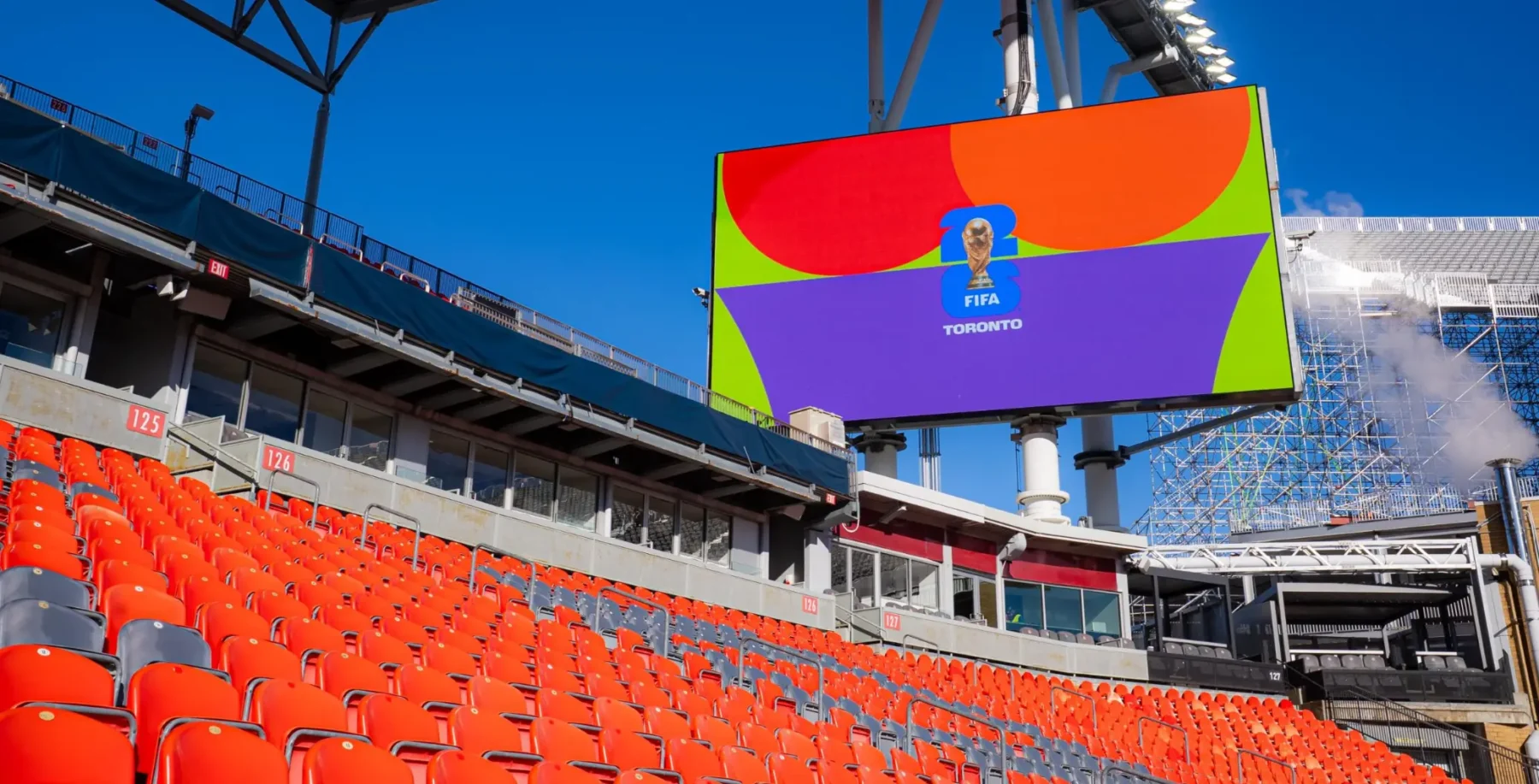 Empty stadium seats at Toronto's BMO Field with a large FIFA World Cup digital screen displaying the FIFA logo and vibrant colors.