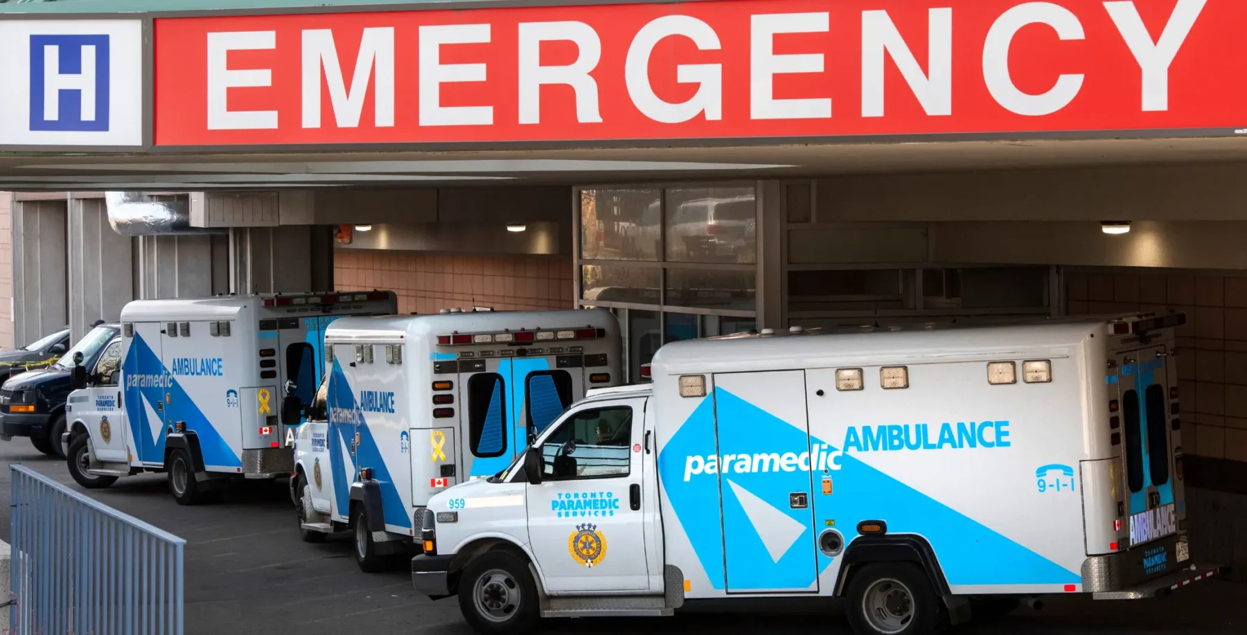 An emergency room entrance with multiple paramedic ambulances parked outside, indicating urgent medical response at a hospital.