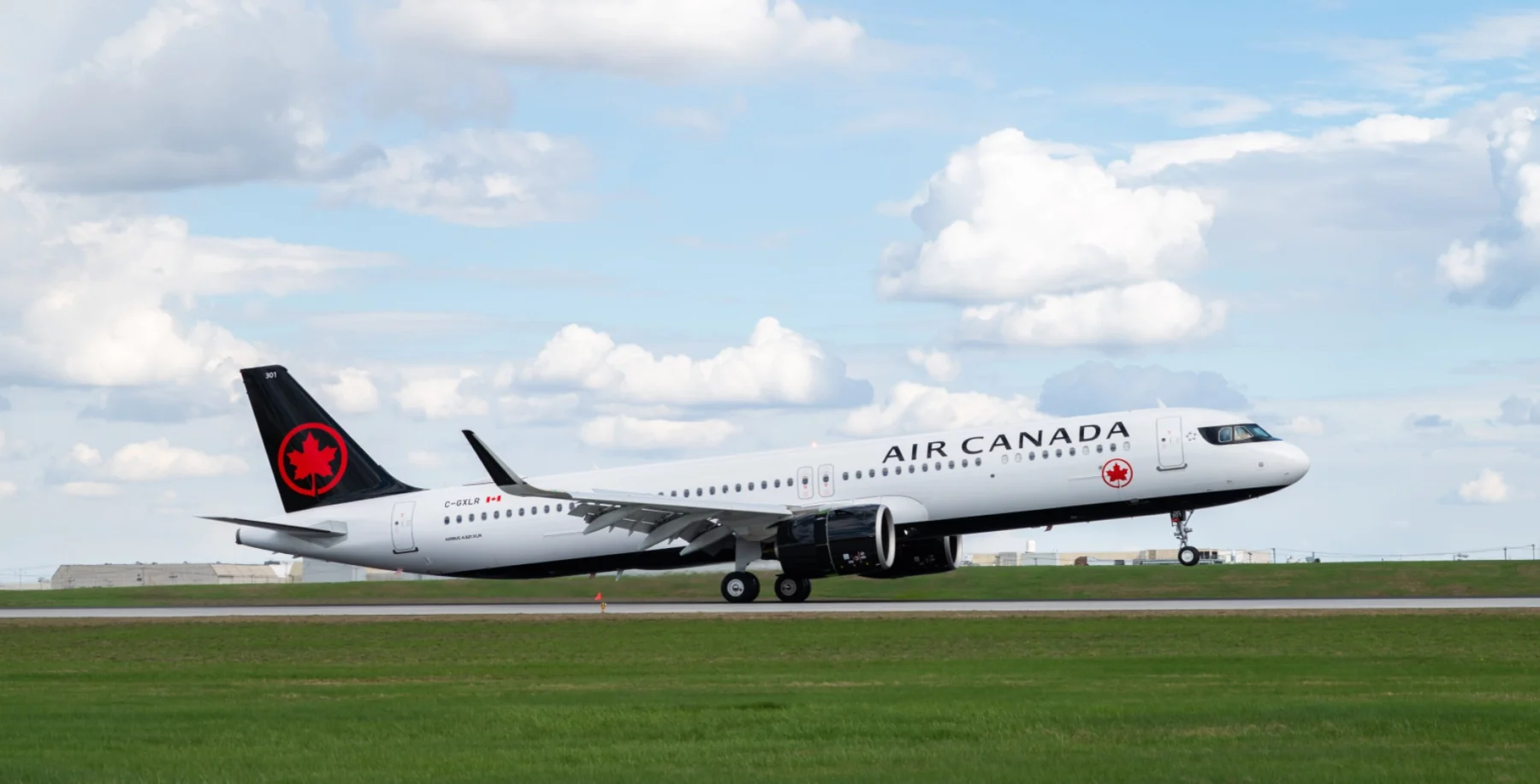 Air Canada commercial airplane taxiing on runway with blue sky and clouds in the background, representing Toronto travel and airline services.