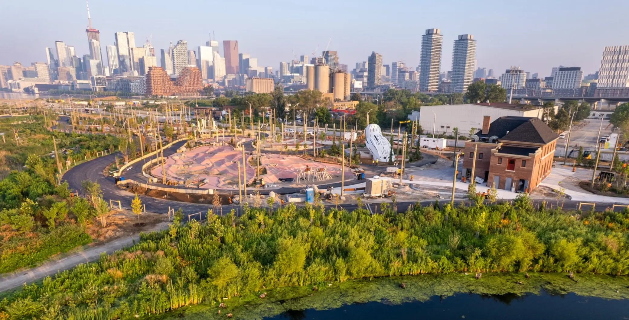 Toronto's Biidaasige Park expansion site with city skyline in the background, showing ongoing development and greenery in the foreground.