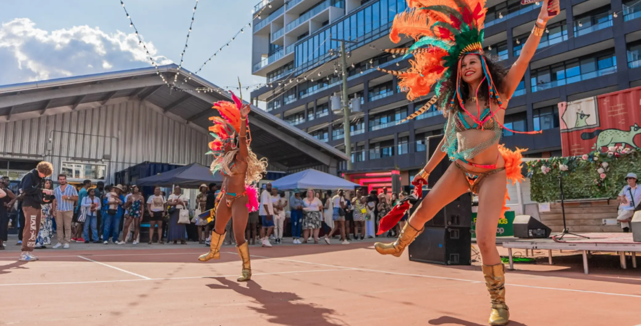 Toronto Caribbean dancers perform at Caribana festival with vibrant costumes and lively street scene in the background.
