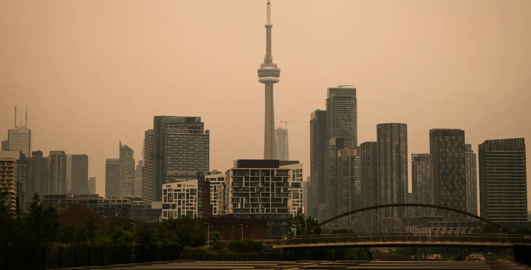 Toronto skyline shrouded in smoke with CN Tower visible amid hazy air, highlighting air quality concerns related to wildfire smoke.