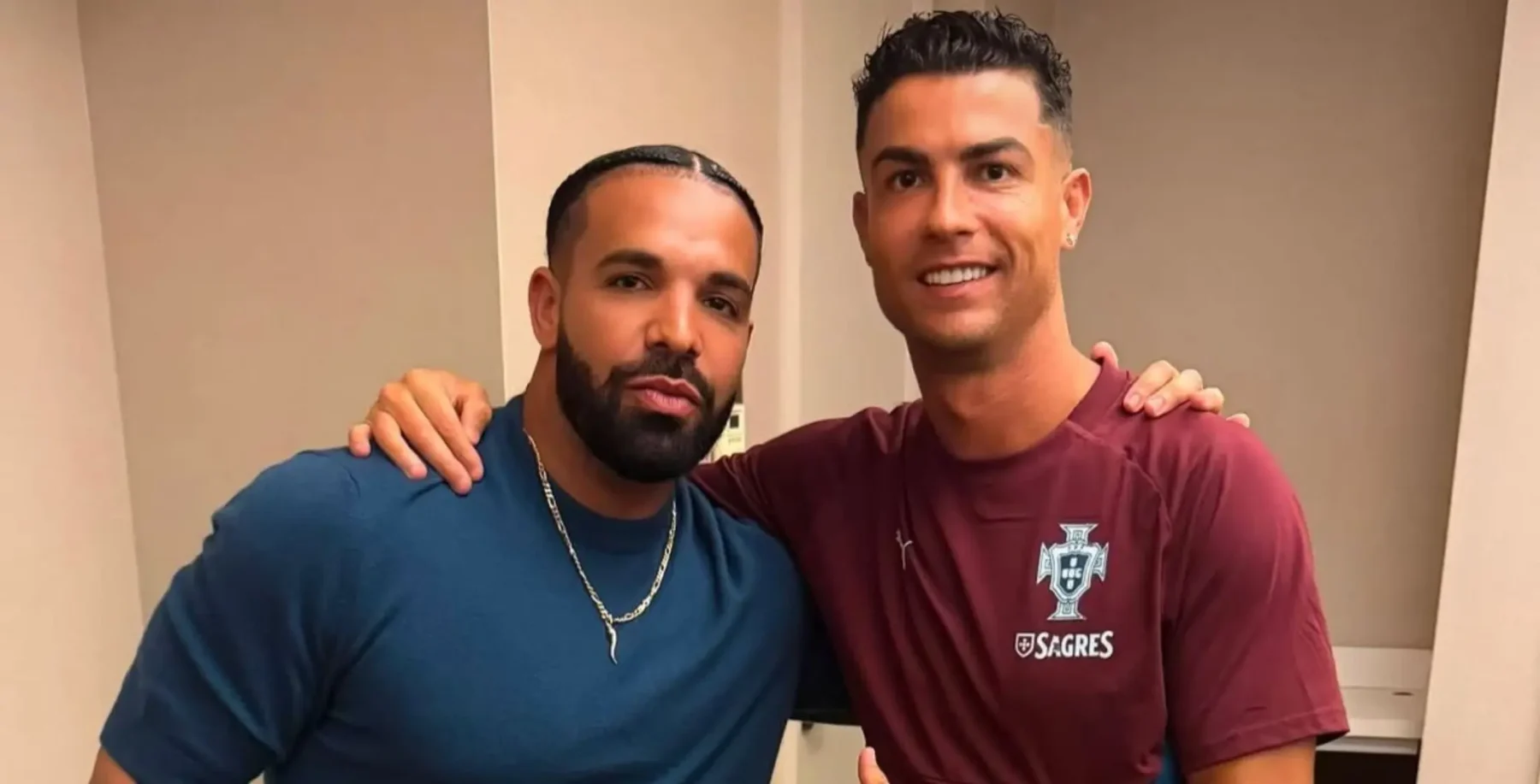 Drake and Cristiano Ronaldo pose together indoors, smiling for the camera, with Ronaldo wearing a maroon soccer jersey.