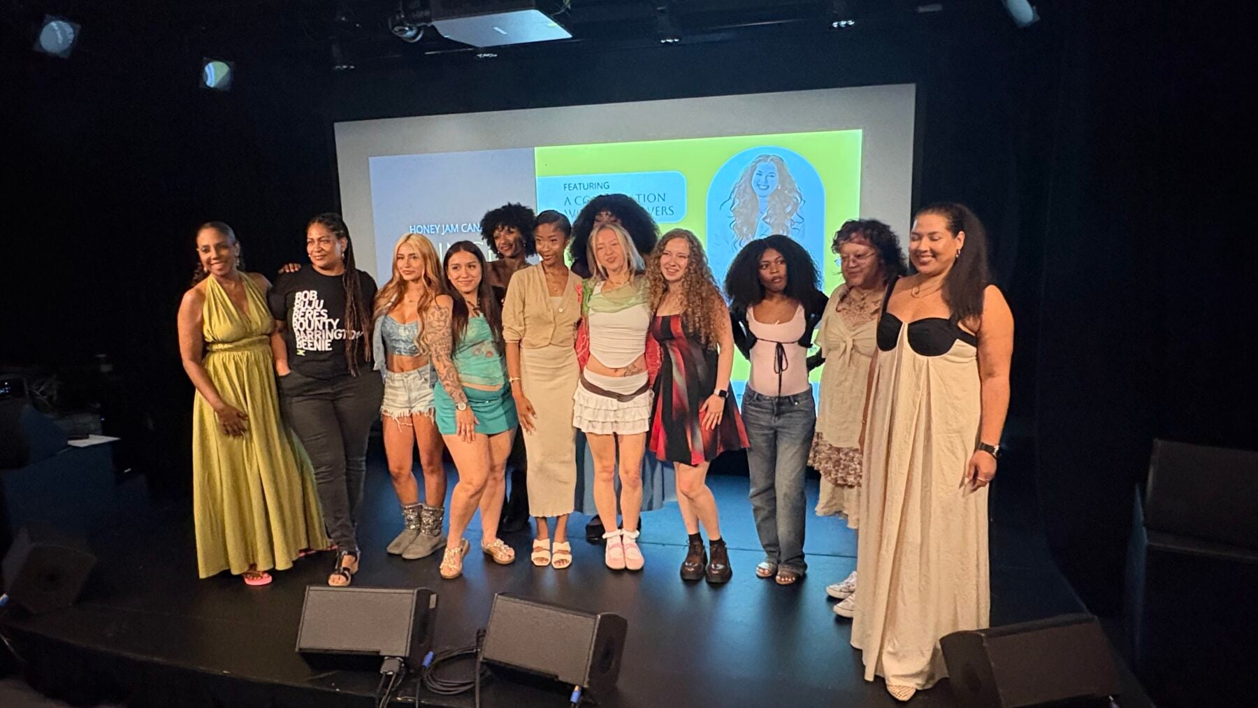 Group of 12 emerging artists at Honey Jam 2026 Toronto showcase, standing on stage with a screen behind them displaying event graphics.