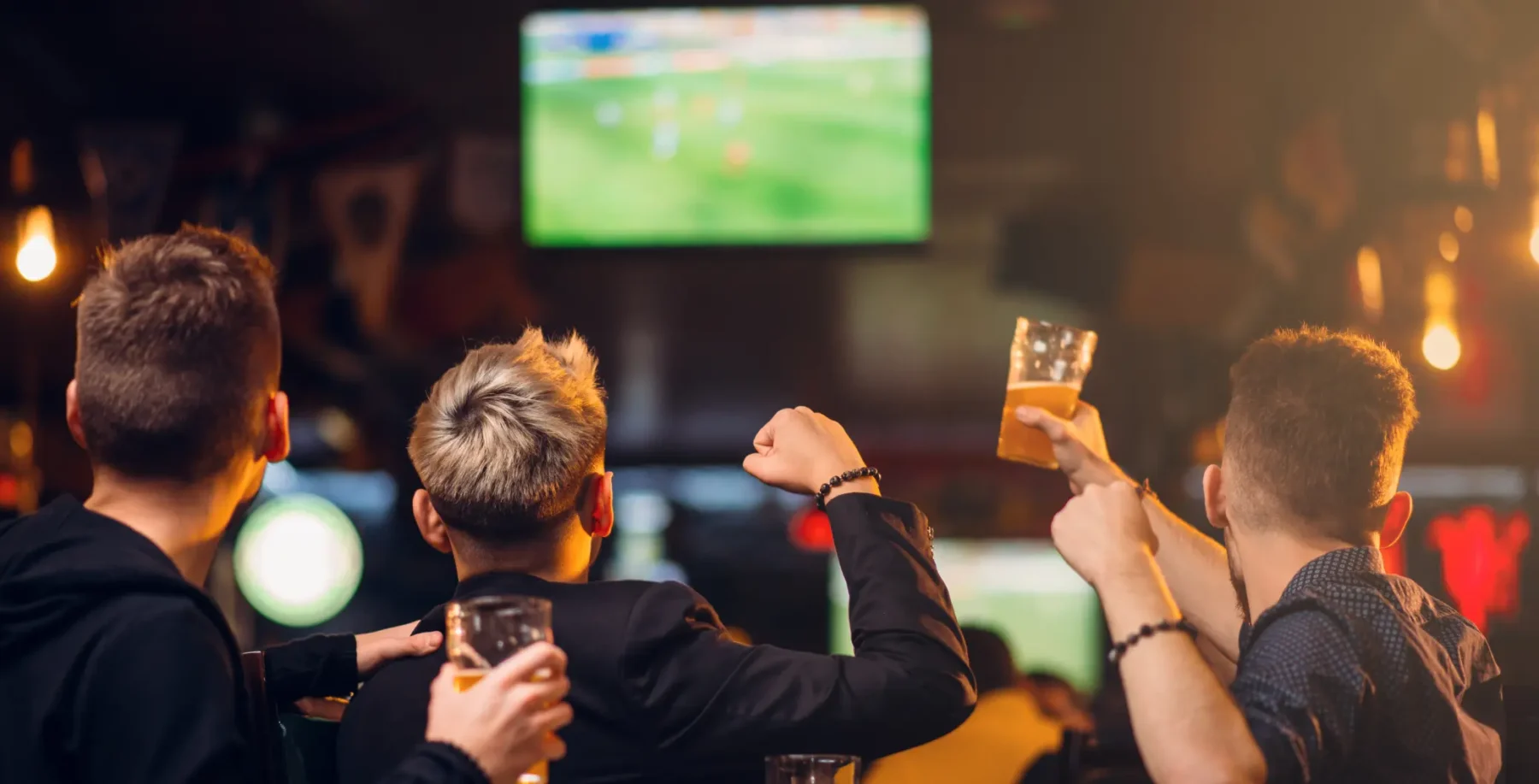 Group of friends watching Canada vs. Morocco soccer match at a Toronto sports bar with drinks in hand.