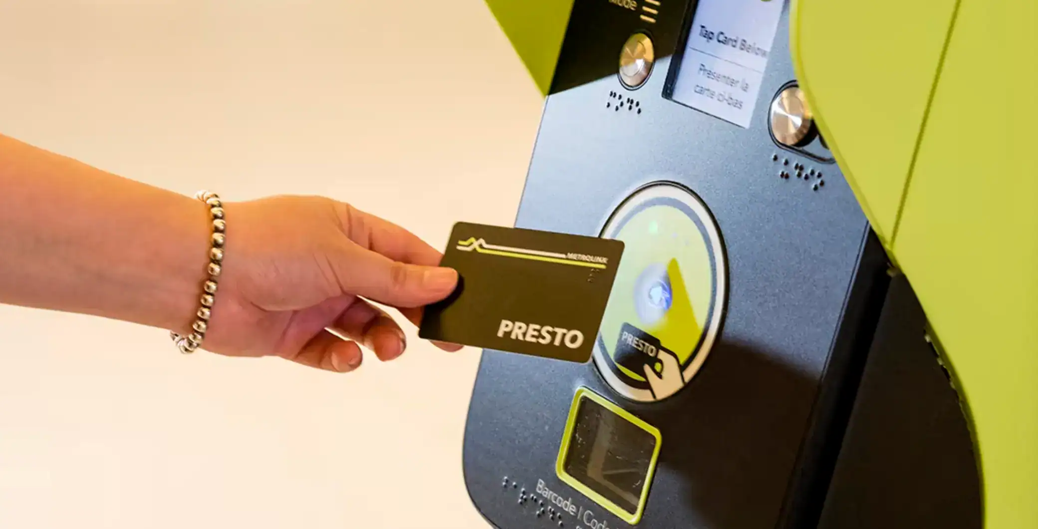 Person using a PRESTO card to tap at a Toronto Transit Commission fare machine for public transit access.