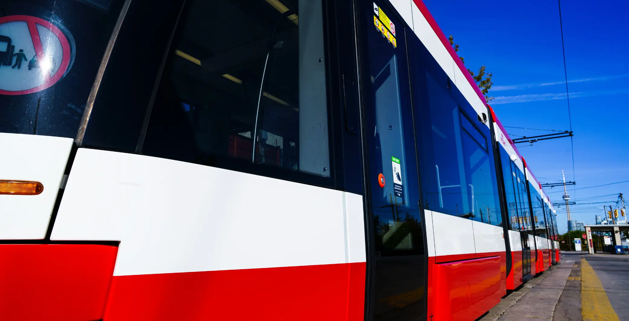 Modern Toronto streetcar with red, white, and black exterior parked on the street under a clear blue sky.