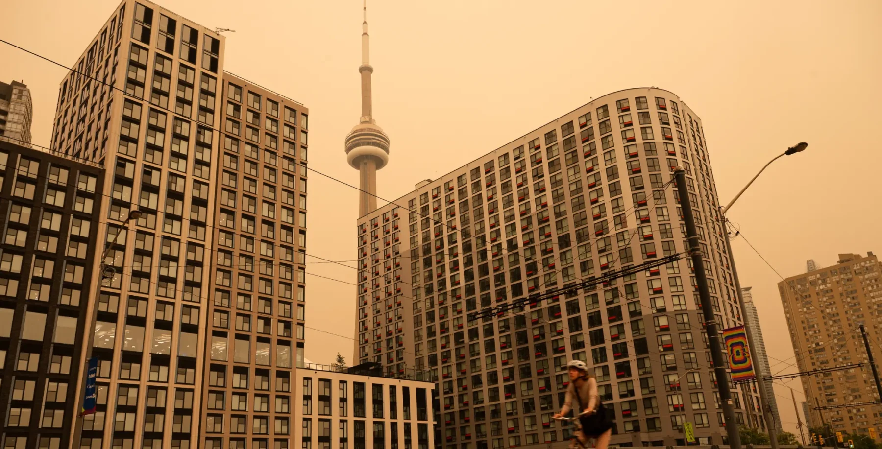 Toronto skyline shrouded in wildfire smoke with CN Tower visible in the background during hazy conditions.