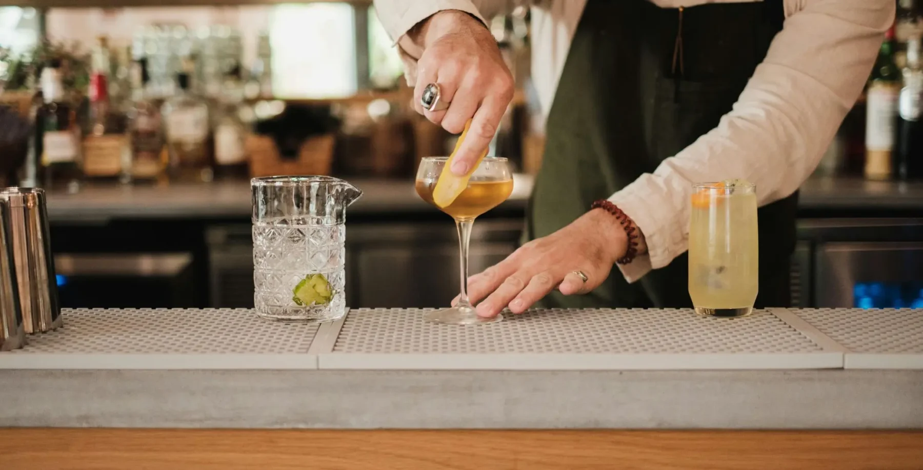 A bartender pours a cocktail into a glass at a Toronto bar, with other drinks on the bar counter, highlighting Toronto's vibrant nightlife scene.