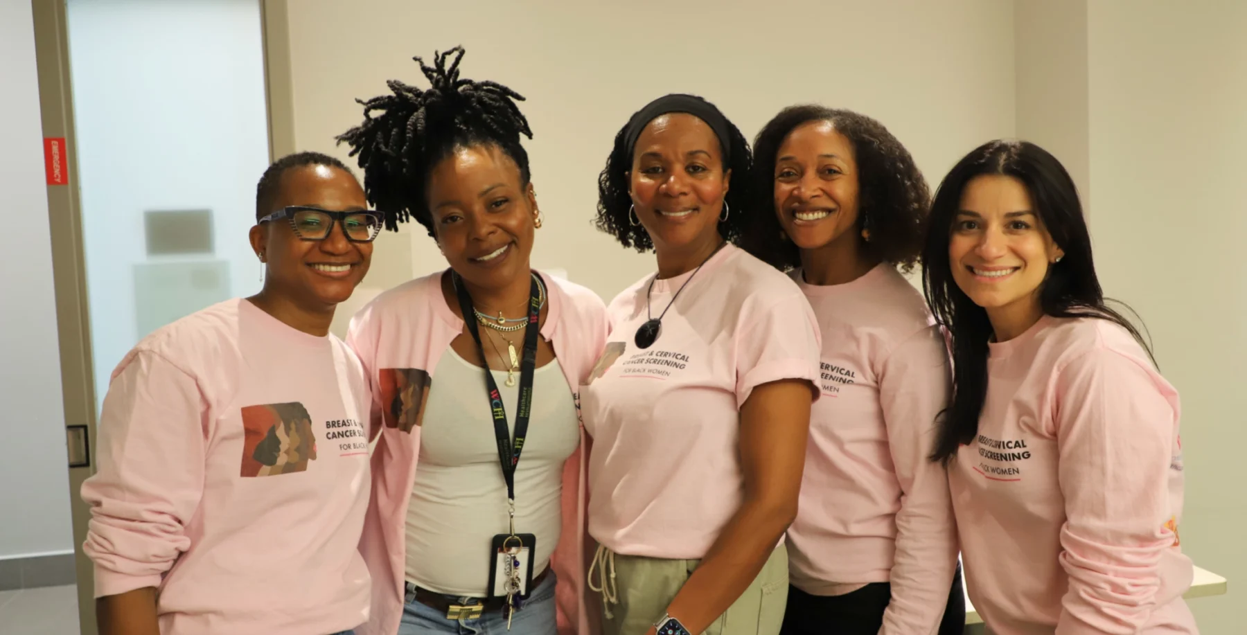 Group of five Black women wearing pink shirts, smiling, at a healthcare event in Toronto.