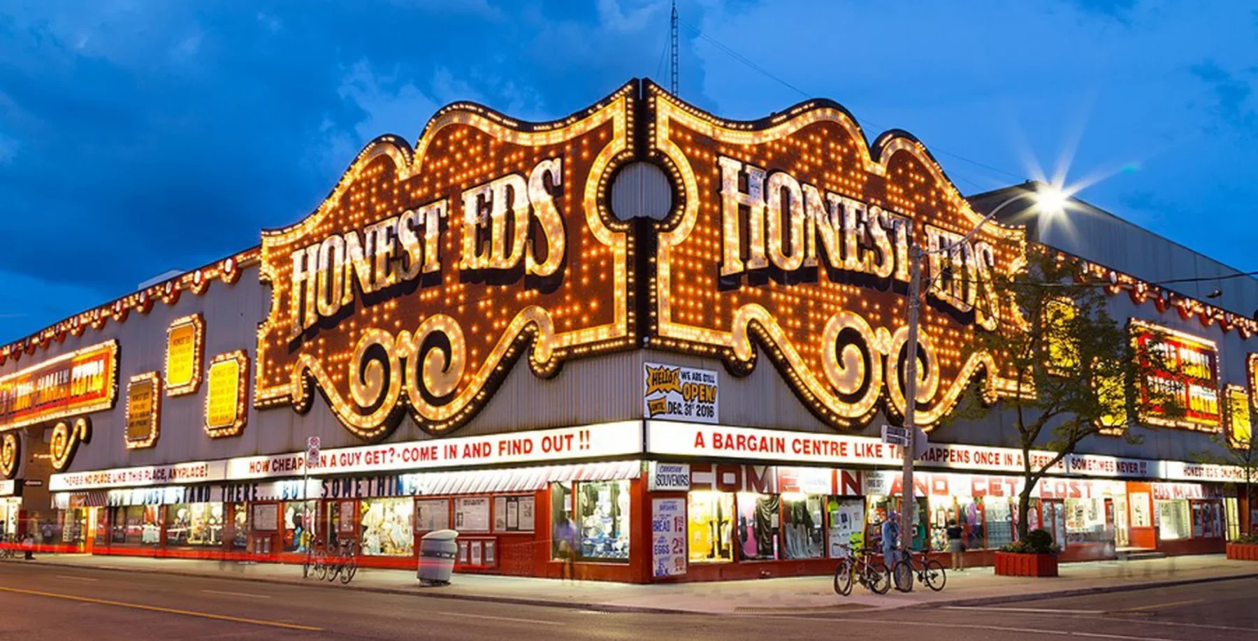 Honest Ed's iconic illuminated sign at dusk in Toronto, a historic discount store known for its vibrant lights and vintage charm.