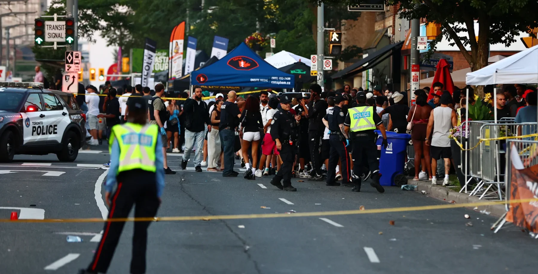 Crowd gathered at the scene of a shooting on St. Clair Avenue, Toronto, with police and emergency responders present after a violent incident.
