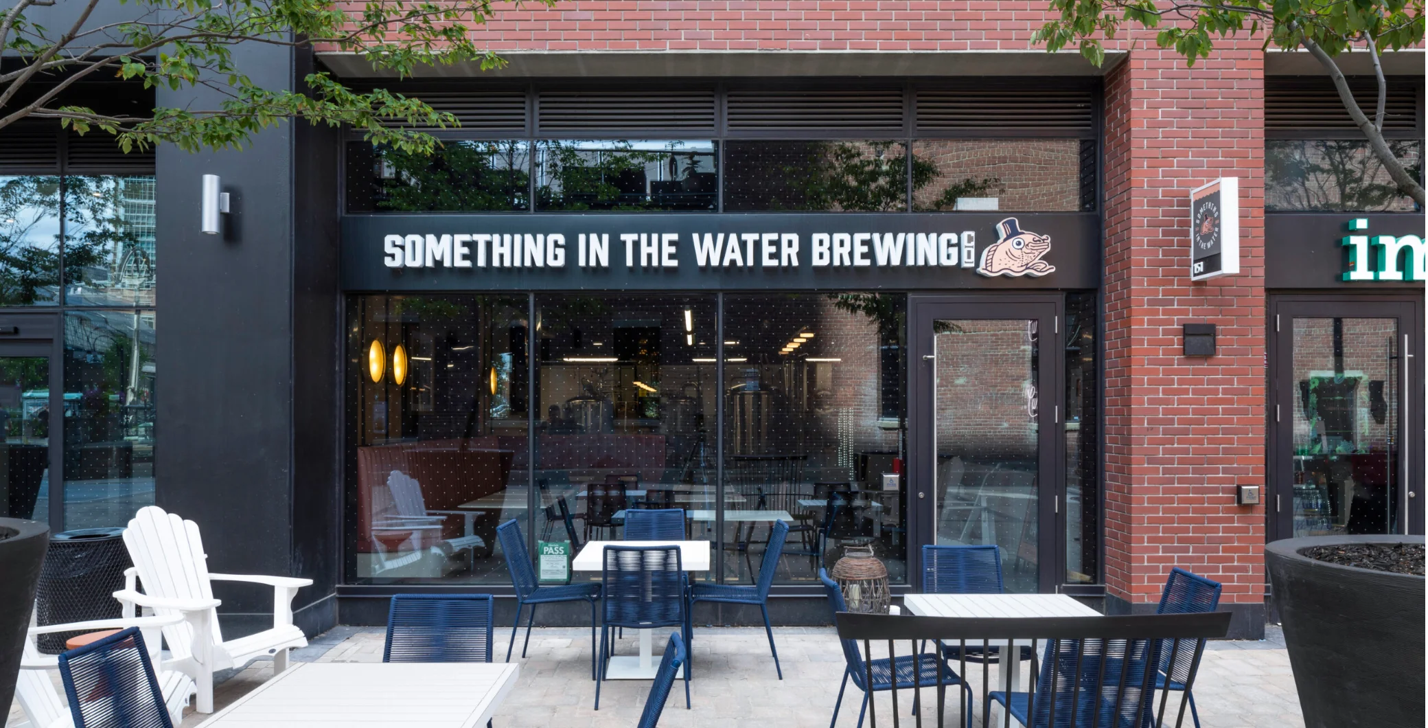 Exterior view of Something in the Water Brewing, a brewery with outdoor seating and a sign displaying its name in Toronto.