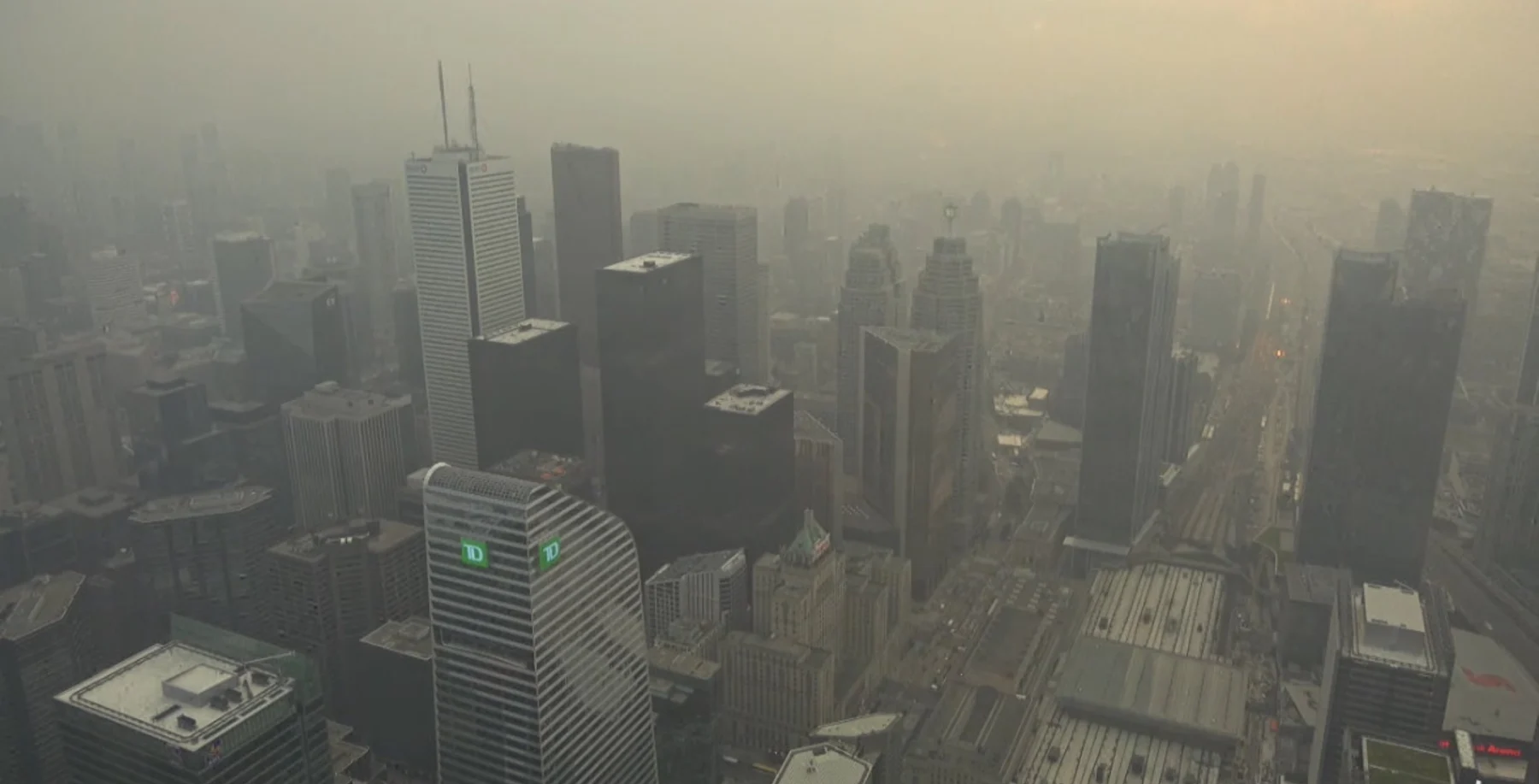 Toronto skyline obscured by smoky haze from Ontario wildfires, with skyscrapers barely visible through the air pollution.
