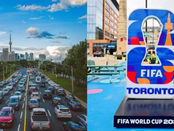 A busy Toronto street with traffic and city skyline, featuring a FIFA World Cup 2026 display, highlighting Toronto's urban environment and sports event presence.
