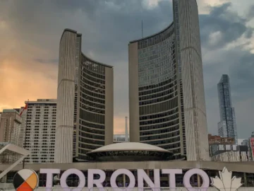 Toronto skyline with modern skyscrapers and the iconic Toronto sign at sunset, showcasing urban architecture and cityscape.